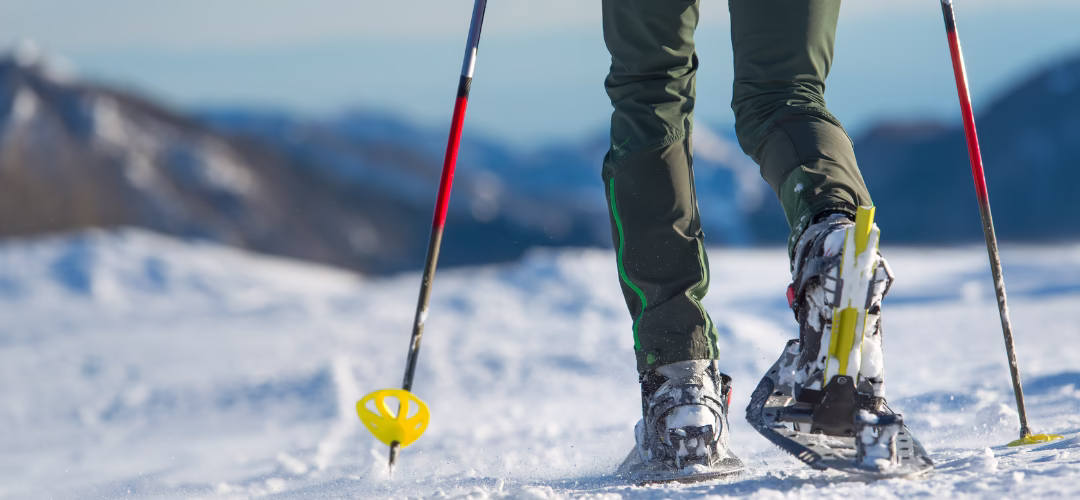 Jambes d'une personne qui marche en raquuette sur la neige