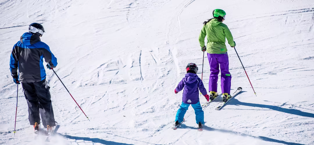 Deux parents avec leur enfant en train de skier