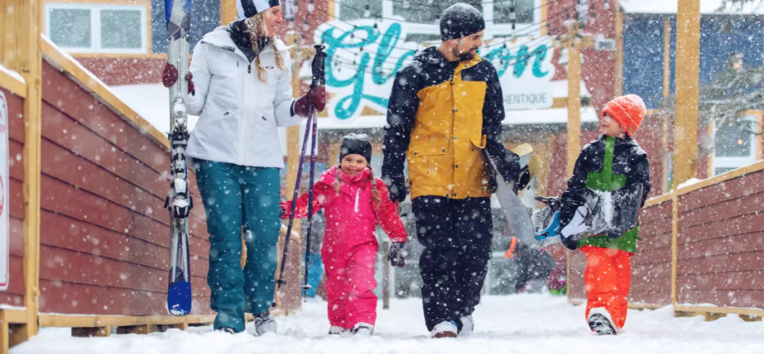 Une famille avec deux enfants sortant avec leurs équipements de ski